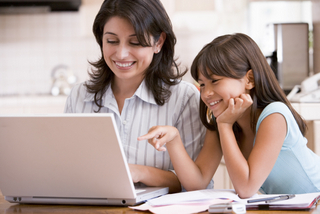 mother and daughter smiling while on a computer