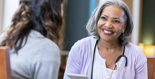 older woman smiling while talking to a another woman