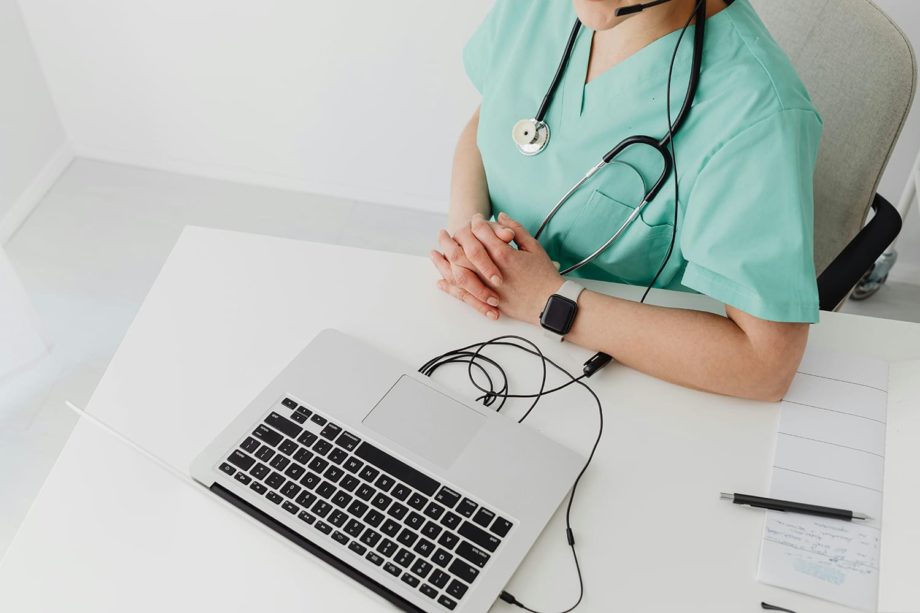 Woman in green scrubs with stethoscope in front of laptop